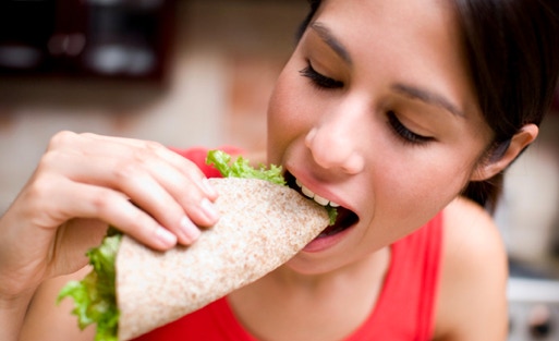 a girl eating a juicy wrap 